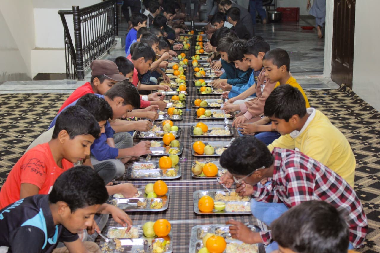 Children receiving freshly prepared nutritious meals at Baqiatullah Foundation
